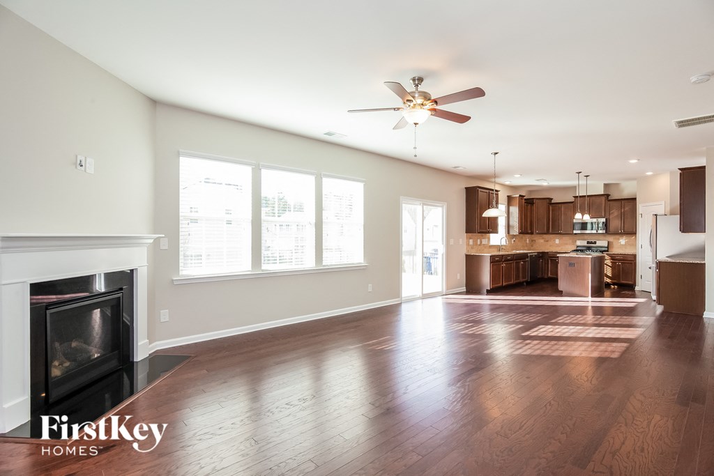 an empty living room with a fireplace and a kitchen
