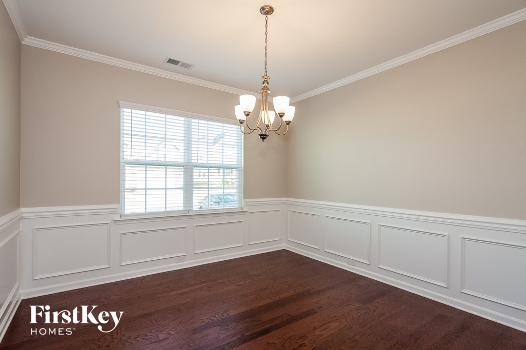 a dining room with white wainscoting and a window
