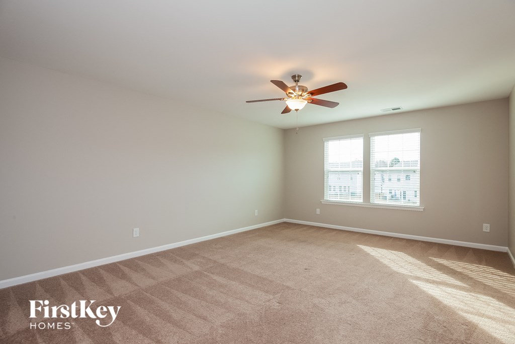 an empty living room with a ceiling fan and a window
