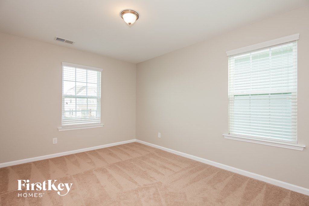 a bedroom with a hardwood floor and two windows