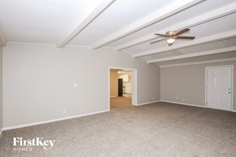 a living room with white carpet and a ceiling fan