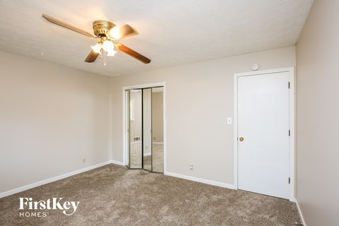 a bedroom with a ceiling fan and a mirrored closet
