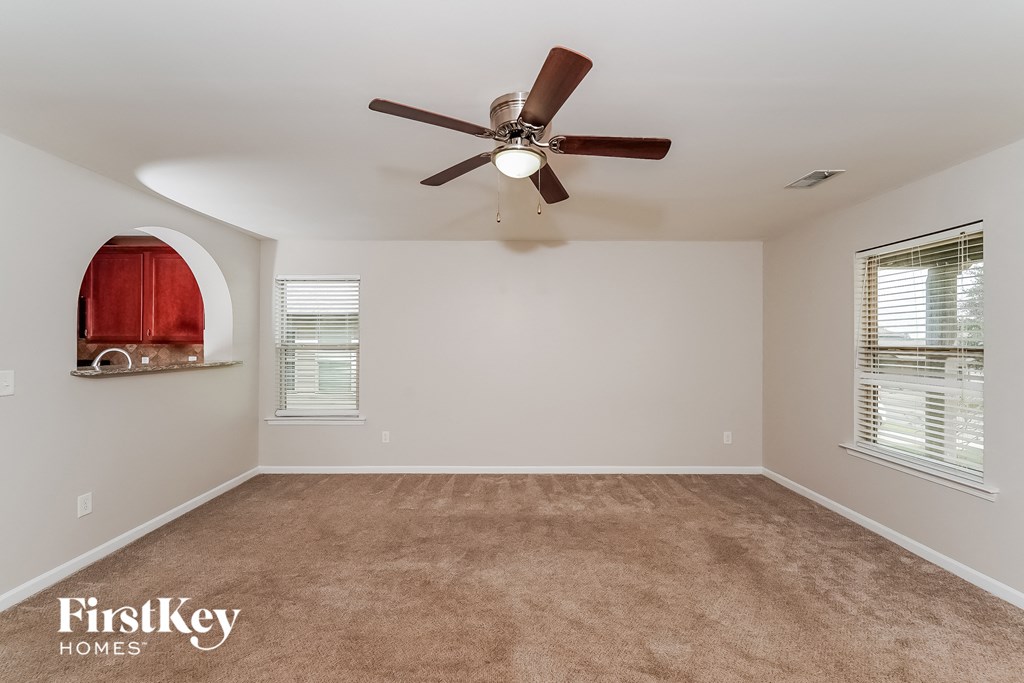 A room with a ceiling fan and carpeted floor.