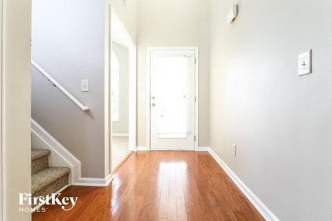 a entryway with stairs and a door to a hallway with hardwood flooring