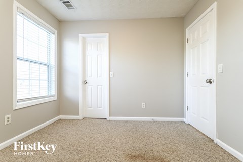 a bedroom with two doors and a window and a carpeted floor