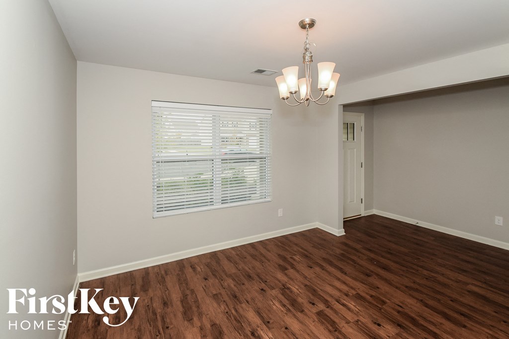 a living room with wood flooring and a window and a chandelier