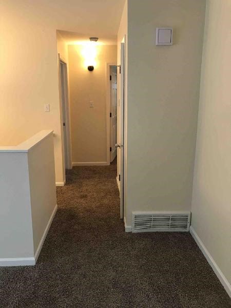 a hallway with a carpeted floor and white walls