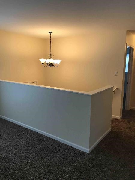 an empty room with a chandelier and a white wall