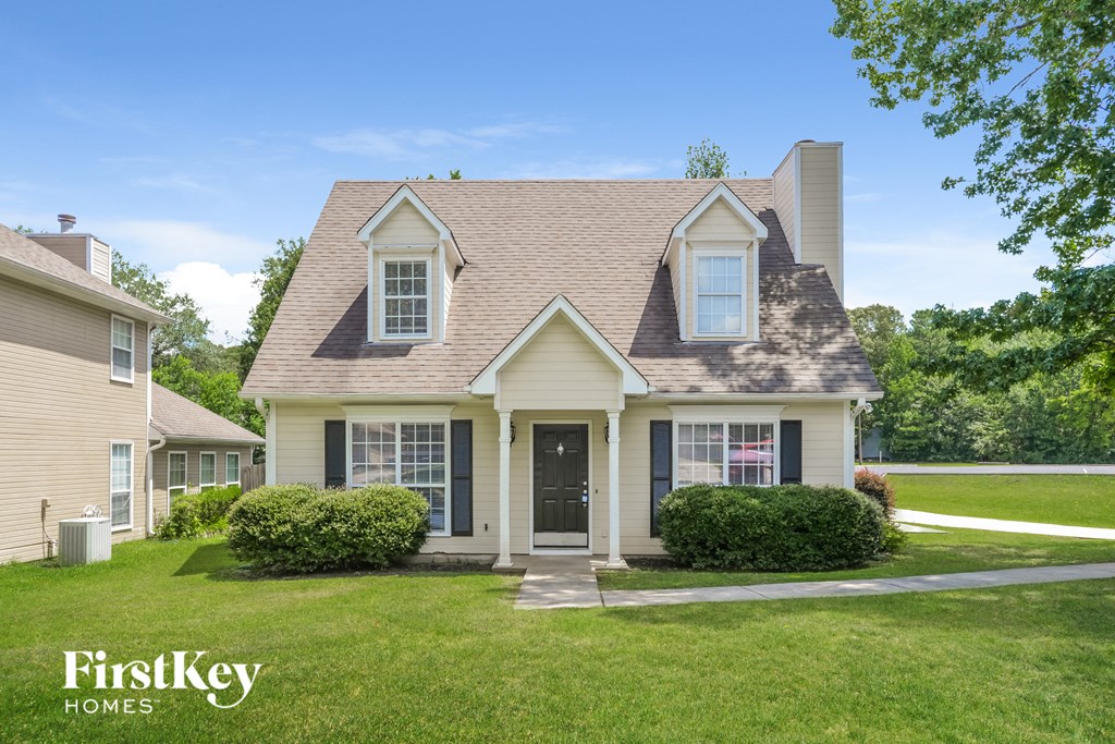 a white house with black shutters and a lawn