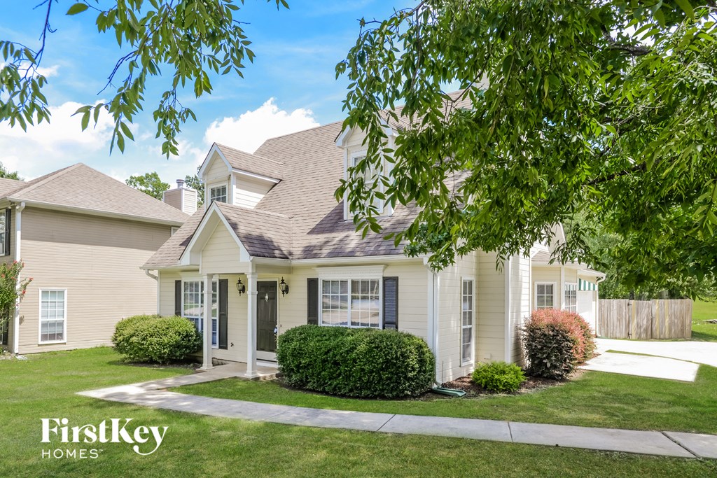 a white house with a lawn and trees