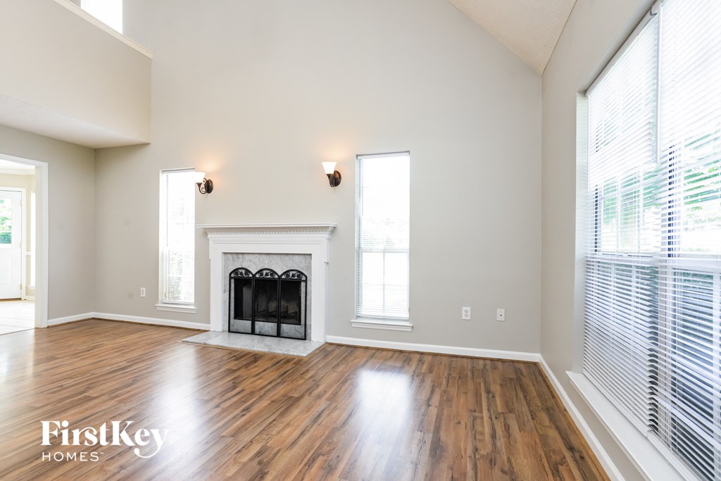 an empty living room with a fireplace and windows