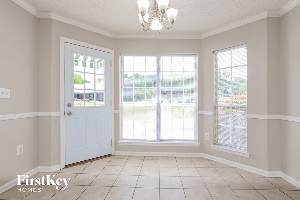 a dining room with a white door and three windows
