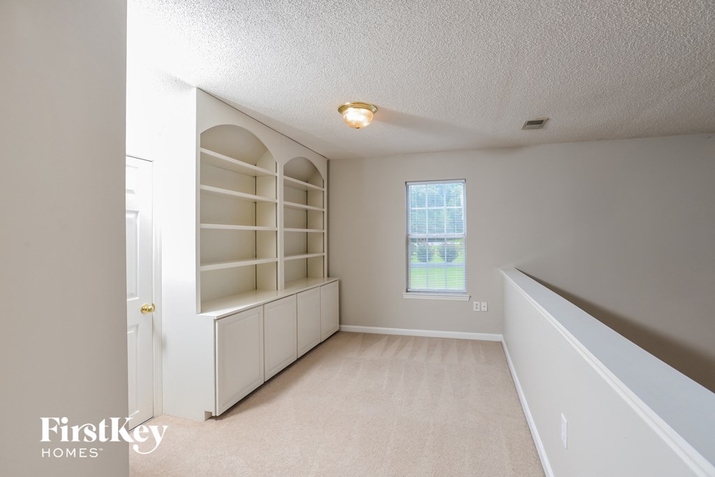 an empty room with white shelves and a window