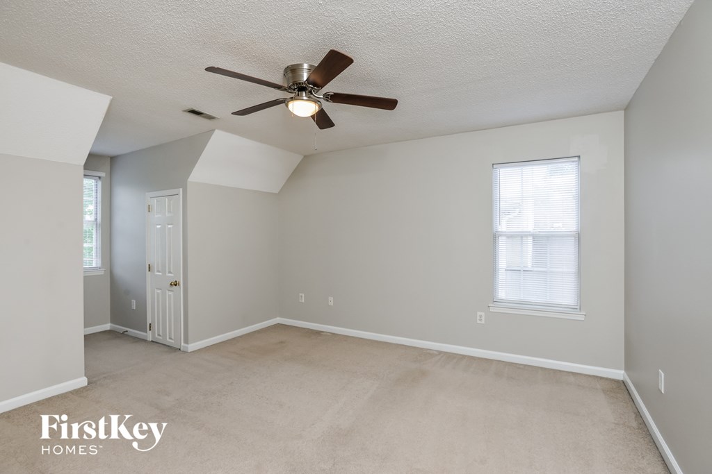 an empty living room with a ceiling fan and a door