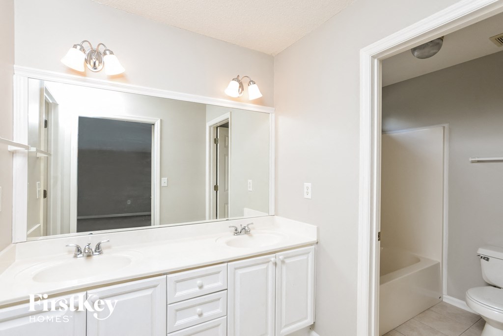 a bathroom with a large mirror and a sink and a toilet