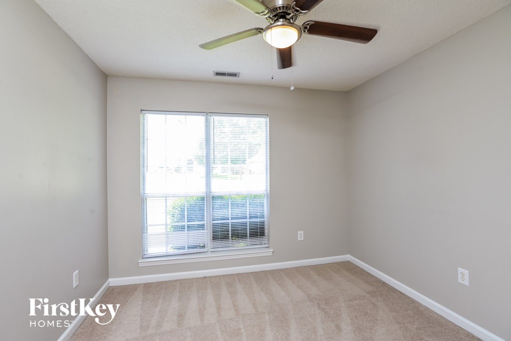 an empty room with a ceiling fan and a window