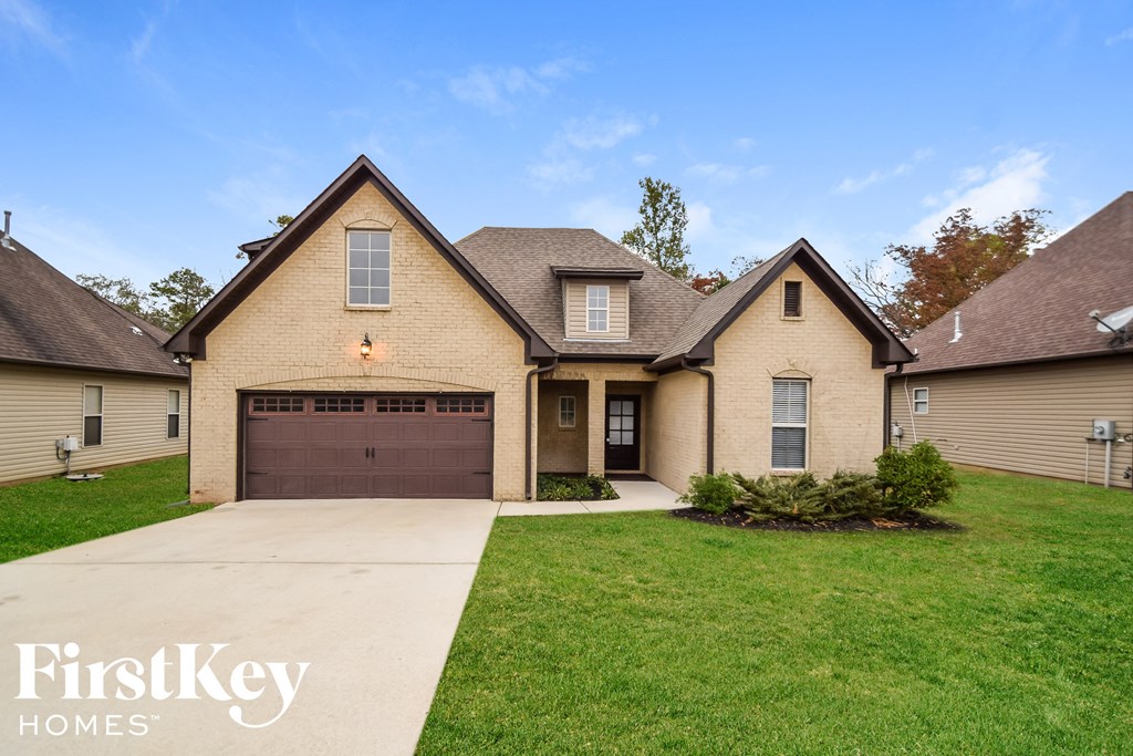 a tan brick house with a brown garage door