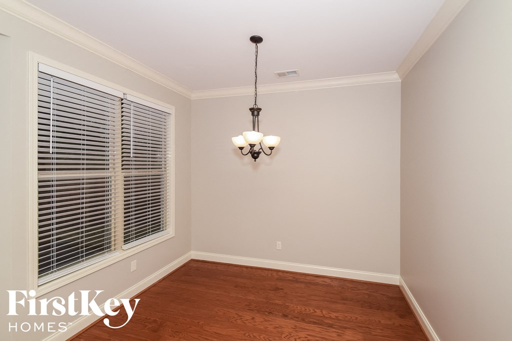 a empty dining room with a large window and a chandelier