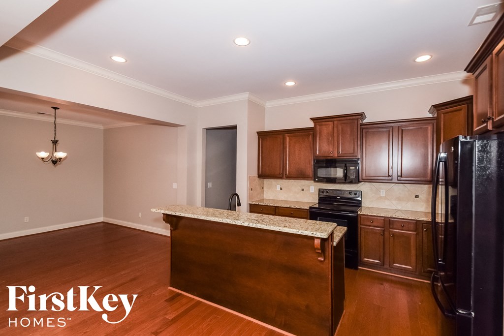 a kitchen with wooden cabinets and black appliances and a granite counter top