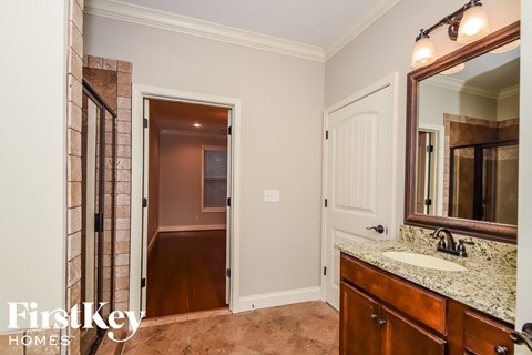 a bathroom with a sink and a mirror and a hallway to a bedroom