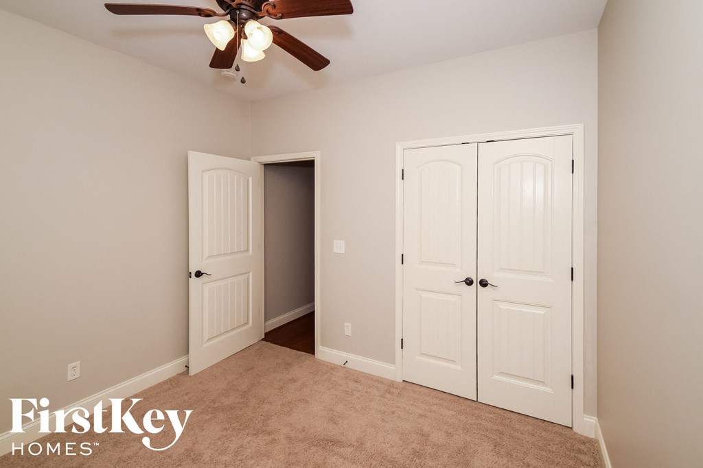 a bedroom with two closet doors and a ceiling fan