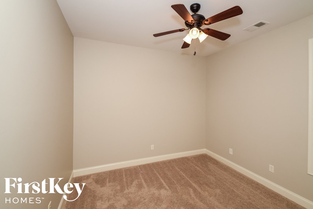 a empty room with a ceiling fan and a carpet