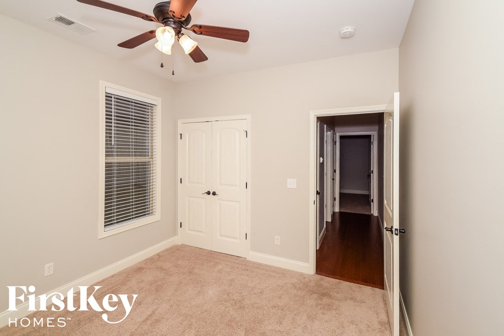 a bedroom with a ceiling fan and a hallway to a closet
