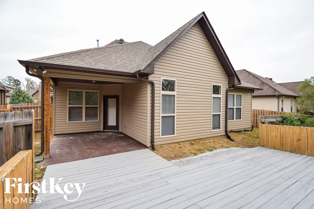 the front of the house with a deck and a wood fence