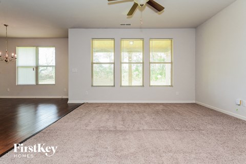 A spacious room with a carpeted floor and a ceiling fan.