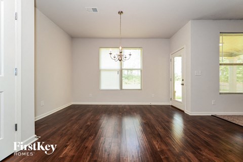 A room with wooden floors and a chandelier hanging from the ceiling.