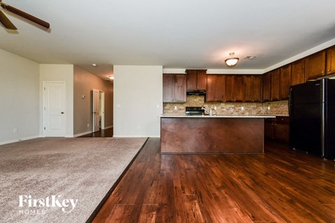 A kitchen with wooden floors and a black refrigerator.