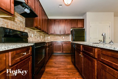 A kitchen with wooden cabinets and a black refrigerator.