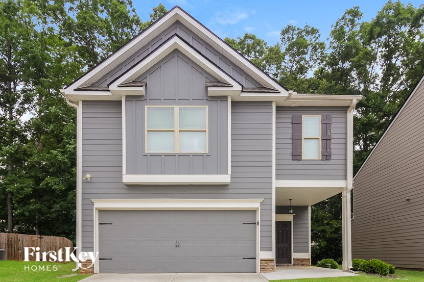 A grey house with a white garage door and a black door.