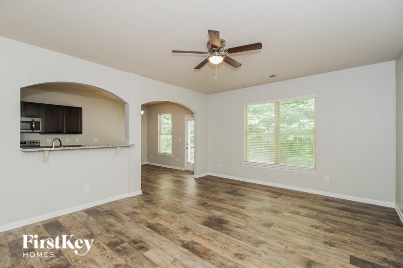 A spacious room with wooden flooring and a ceiling fan.