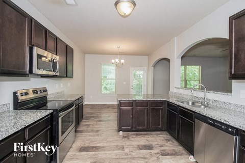 A kitchen with dark brown cabinets and a granite countertop.