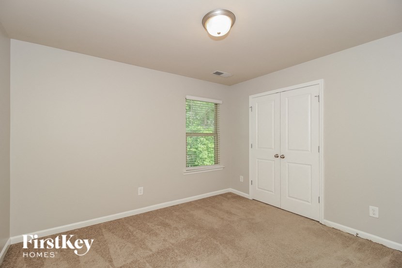A room with a white door and a window with a view of trees.
