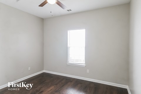 a bedroom with white walls and wood floors and a window