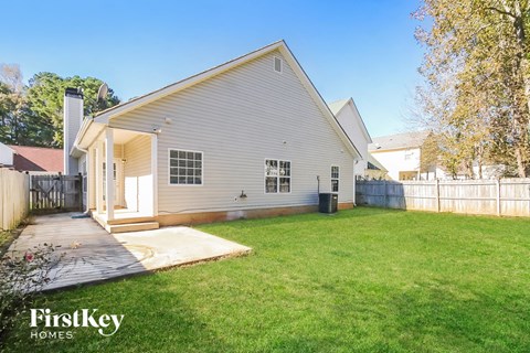 a white house with a grass yard and a deck