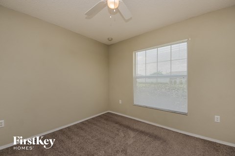 a bedroom with a large window and a ceiling fan