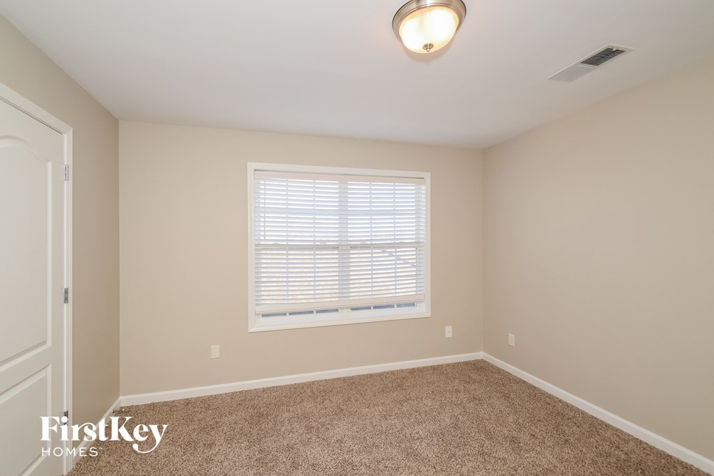 a bedroom with beige carpet and a window
