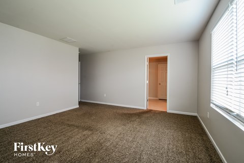 a master bedroom with a carpeted floor and a large window