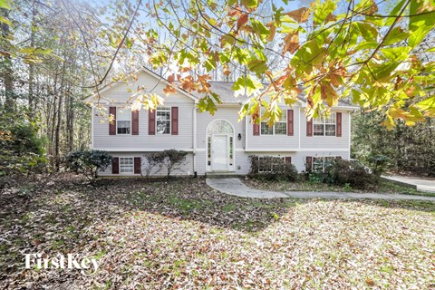 a white house with red shutters and a yard with fallen leaves