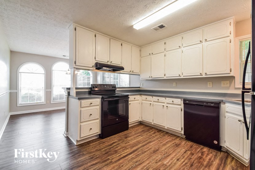 a kitchen with white cabinets and black appliances and a wood floor