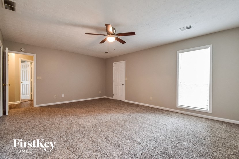 the spacious living room with ceiling fan and carpeting
