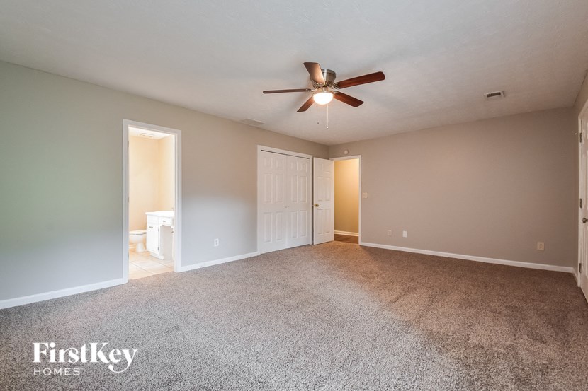 a spacious living room with carpet and a ceiling fan