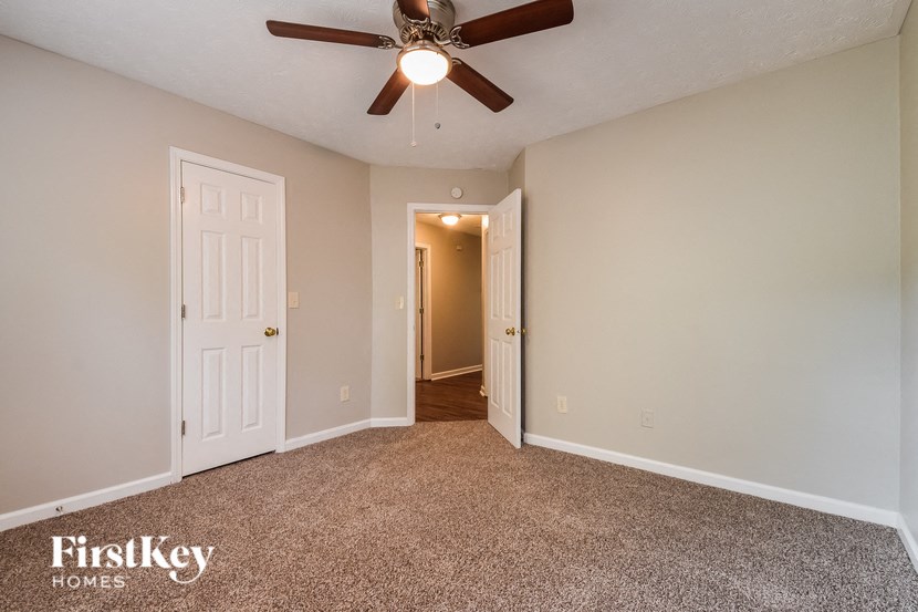 the spacious living room with ceiling fan and carpeting