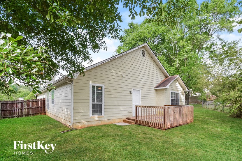 a small white house with a yard and a wooden fence