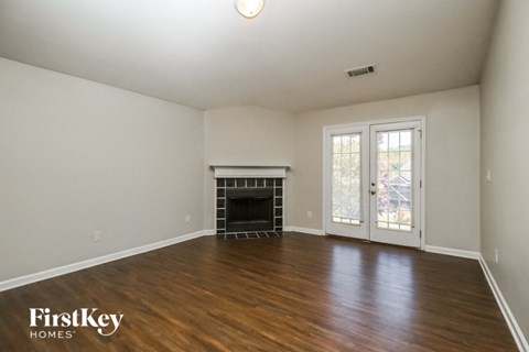an empty living room with a fireplace and wood flooring