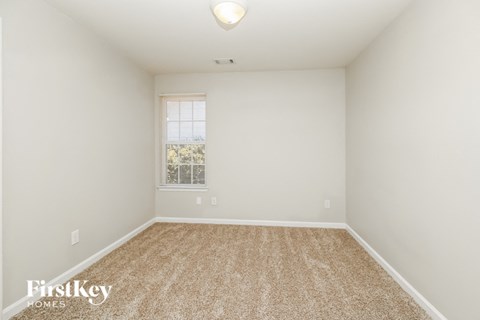 a spacious room with carpet and a window