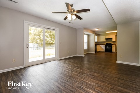 A spacious room with a ceiling fan and wooden flooring.